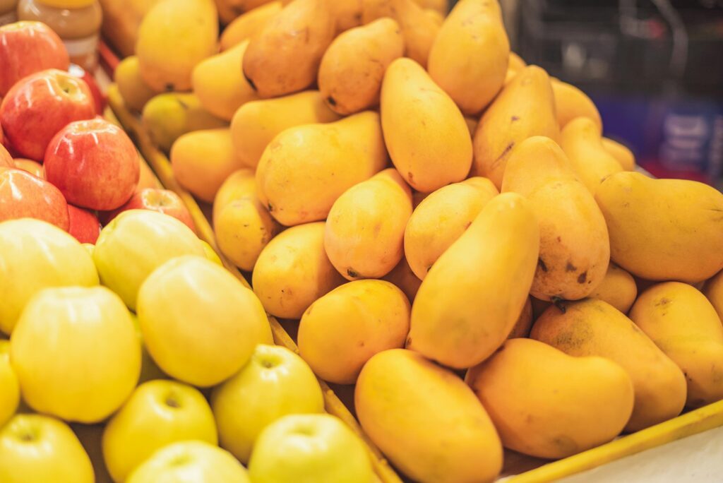 A vibrant display of fresh apples and mangoes in a supermarket's fruit section.